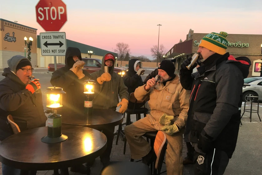 East Grand Forks Mayor Steve Gander, seated at the table, has a morning drink with a group of friends, to highlight Minnesota Gov. Tim Walz's executive order that permits outdoor dining in the winter, as a way for business to operate.